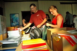 Oskaloosa School Board Members Tom Richardson (left) and Laurie Fiscella (right) help fill backpacks for area students Wednesday night.