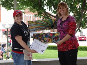 Melynda Van Zee (on the right) was presented the $500 Fine Arts and Cultural Entertainment (FACE) cash award for these two acrylic paintings.  Making the presentation at Main Street Oskaloosa's Art on the Square is Briana Bartlett, FACE member. (submitted photo)