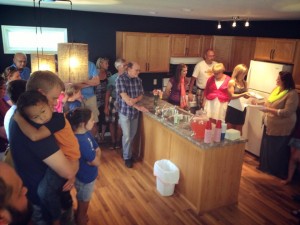 Mahaska County Habitat for Humanity Executive Director, Valinn McReynolds, hands a Bible and house keys over to new homeowner Nichole Montavon. Friends and family gather in the new home for the dedication. (photo courtesy CRI)