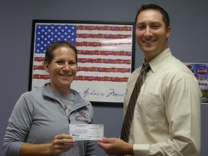 Oskaloosa PE Teacher Betsy Luck receives a check from Kiwanis Club member Kent Peterson. (submitted photo)
