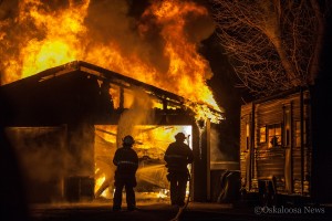 Oskaloosa firefighters Tim Nance and Scott Howard tackle the flames Sunday evening.