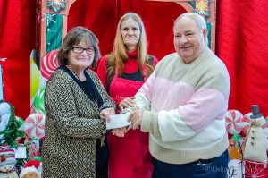 Cindy Krusmark (Mahaska Drug) (Left) and Jerry Morrison (Salvation Army)(Right) and Kim Spoelstra (back) present a check to help provide presents for Mahaska County kids this Christmas season.