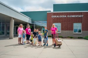 Kelly Saville (far left) and the kids from her daycare and teachers help haul in the dozens of books collected for the summer reading program.)