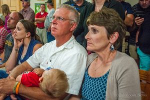 Russ Van Renterghem (left in white shirt) and his wife Beth watch election returns come in at the Mahaska County Courthouse on Tuesday night. 
