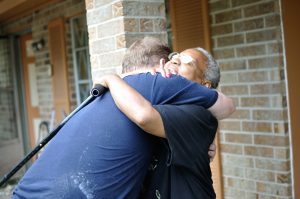Carrie Russ hugs one of the Biloxi team members as they work on gutting her home that suffered flood damage.