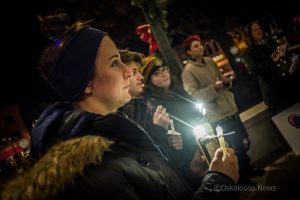Over a dozen people took part in a Transgender Day of Remembrance vigil on Monday evening. The November winds prevented flames from lighting the candles, so participants used cellphone flashlights instead.