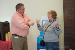 Skip Joelson of MidAmerican Energy speaks with a customer on Friday about the new kiosk located at Penn Central Mall.