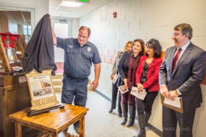 Oskaloosa firefighter Mark Tennison unveils the new brass plaque that will help residents and visitors alike learn more about Oskaloosa buildings.