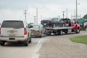 A tow service is seen here with a black Chevrolet Malibu and a Nissan being escorted by Poweshiek County Deputies just moments before the press conference on Tuesday afternoon.