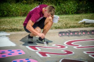 Casey Hill paints his number on 'Indian Trail' to start his senior year at Oskaloosa High School. (photo by Ginger Allsup)