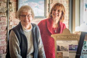 Emily Russell (left) and Ann Fender (right) unveil the building plaque that will hang on the front of the Centennial Block on the north side of the Oskaloosa square.