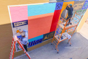 Chicago artist Michael Ferrarell and his assistant work on the mural on the north side of the Oskaloosa Square on June 21st, 2021.