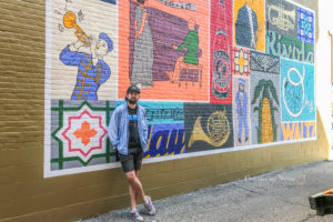 Chicago artist Michael Ferrarell stands in front of his completed mural on the north side of the Oskaloosa Square.