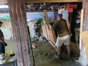 Volunteers help clean up the basement of Eldon City Hall this past week after floodwater damaged the structure.