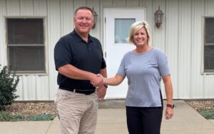 Clow Valve Company VP, General Manager, Mark Willett with OISC Board President, Laura North, in front of the new OISC facility located at 1336 12th Ave. E. 