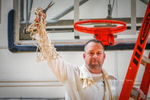 William Penn Men's Basketball Head Coach John Henry holds the net from the team's sixth in seven years conference championship.