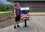Brody Barnhart stands with one of his flag collection boxes. This one is a the Mahaska County Environmental Learning Center. The other is at the VFW facility in Oskaloosa.
