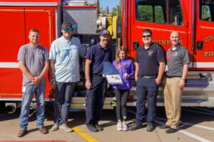 Lily Woods (center) with a certificate and other donations she received to recognize the good job she did in reporting a recent fire.