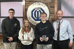 Optimist Club of Oskaloosa honored two seventh grade students Wednesday as the Students of the Trimester. Club Members Clint Gingrich, left and Mark Scholes, far right, presented the plaques to Lauren McKain and Edward Rust. 