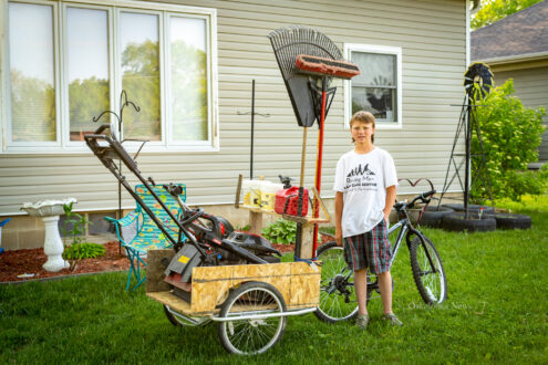 Levi Jarvis stands with his bicycle and trailer he uses to mow lawns for those in need.