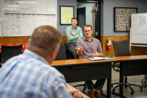 Iowa's Lt. Governor Adam Gregg (seated at table) speaks with Mark Willett (foreground) at Clow Valve Foundry location on Thursday.