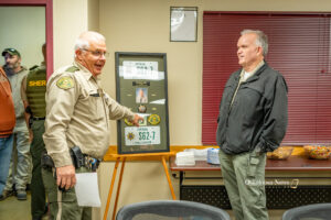 Sheriff Russ Van Renterghem (left) and Deputy Scott Miller (right) at the presentation of a shadow box in honor of Miller's retirement on Tuesday.