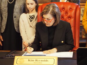 Iowa Gov. Kim Reynolds signed into law a bill removing the state’s gender-balance requirement for state boards and commissions on April 3, 2024 at the Iowa State Capitol. (Photo by Robin Opsahl/Iowa Capital Dispatch)
