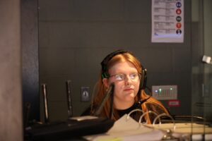 Students operate the control booth at the George Daily Auditorium, honing their technical skills. Funding from the Learning Beyond the Bell grant will provide for upgrades and new learning opportunities for Oskaloosa Middle School students exploring their passion for theatrical arts. Meanwhile, middle school cooking club participants engage in the summer 2023 'Barbecue 4 Badges' event. Students are set to return this summer equipped with new equipment for continued engagement opportunities in after-school programming at the Oskaloosa Middle School. 