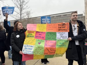 From left, Olivia Sawyer and Jeremy Bauer-Wolf protest the U.S. Education Department’s mass layoffs during a “honk-a-thon” and rally March 14, 2025, in Washington, D.C. (Photo by Shauneen Miranda/States Newsroom)