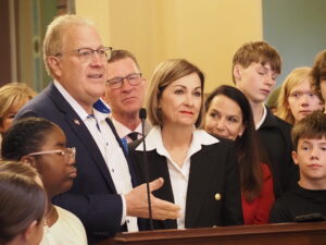  Mike McGrory, left, superintendent of the Ottumwa Community School District, thanked Gov. Kim Reynolds as she signed into law a bill setting a statewide minimum ban on cellphones during instructional time at public K-12 schools. (Photo by Robin Opsahl/Iowa Capital Dispatch)