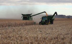 Machinery harvests corn in Scotts Bluff County, Neb., last year. Low prices for row crops and high costs for fertilizer are squeezing Midwest row-crop farmers while the Southeast is still on an economic winning streak, according to a Stateline analysis of federal economic data for the first quarter. (Photo by Gary Stone, Nebraska Extension/Courtesy of University of Nebraska-Lincoln)