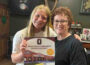 Oskaloosa High School Student Council freshman Camryn Bowie delivers a copy of the council’s new K-12 activity calendar to Madonna Bowie, owner of Bridget’s Public House and one of the local business sponsors whose coupons are featured in the calendar. Proceeds from the $20 calendar support student leadership programs at Oskaloosa Schools.