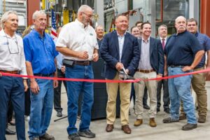 Mark Willet center with scissors, cuts the ribbon on Clow Valve's newest addition to their foundry in Oskaloosa, Iowa.