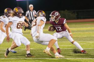 Oskaloosa quarterback Tyler Edgar scrambles from Mt. Pleasant defenders on Friday night.
