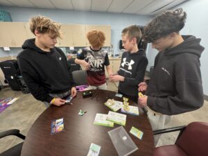 Several Oskaloosa Middle School students work side by side to build, wire, and run a robotic snake as Musco Lighting engineers circulate among the groups, answering questions and cheering student successes. The room buzzed with energy as teams tested their designs, made quick adjustments, and celebrated progress together during Oskaloosa Schools Innovators Quest.