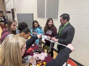 Oskaloosa Middle School students shake hands and talk with local professionals during the school’s Career Walk, part of Career Day. The event gave students the chance to connect with community businesses and learn about a wide range of careers while practicing professional skills like introducing themselves and asking questions.