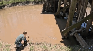  Ryan Kunkle collects water from the Middle River in Warren County to test for nitrates. (Screenshot from video by Zach Sommers for Iowa Capital Dispatch)