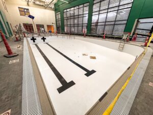 Crews work through the final phase of construction inside the Mahaska County YMCA’s new pool facility, where detailed finish work, mechanical systems, and splash pad features are being installed ahead of a projected late-August completion and September opening.