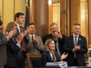 Iowa Gov. Kim Reynolds, joined by Republican leaders in the state Senate and House, signed a measure into law May 18, 2026, aimed at lowering property taxes. (Photo by Robin Opsahl/Iowa Capital Dispatch)