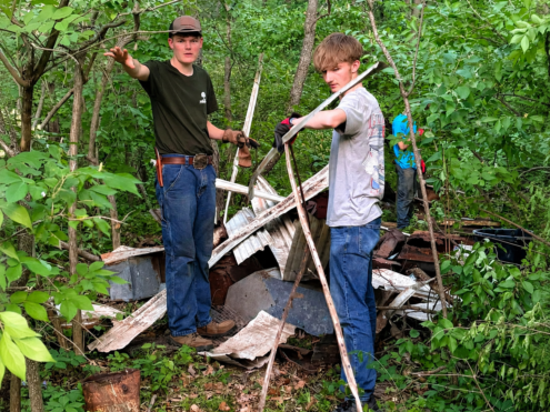 Wyatt DeCook, left, and a friend remove scrap metal and other discarded materials from a wooded area at Cedar Bluffs Natural Area near Oskaloosa. DeCook and several volunteers have removed more than 2,600 pounds of metal and debris from the conservation area in recent weeks.