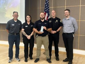 Oskaloosa Police Officer Logan Nord, center, holds the 2026 Iowa Association of School Resource Officers School Resource Officer of the Year award. Oskaloosa Police Chief Ben Boeke and Oskaloosa City Manager Shawn Metcalf are pictured to Nord’s left during the award presentation. Photo submitted.