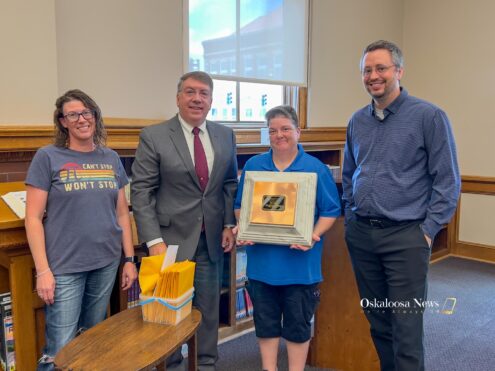 Mayor David Krutzfeldt, second from left, Oskaloosa Library Director Marion Gaughan, holding the lid, and City Manager Shawn Metcalf, right, during the America 250 Time Capsule sealing ceremony on July 21, 2026. The capsule contains 22 envelopes submitted by local residents and organizations and is scheduled to be opened July 4, 2076.