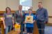 Mayor David Krutzfeldt, second from left, Oskaloosa Library Director Marion Gaughan, holding the lid, and City Manager Shawn Metcalf, right, during the America 250 Time Capsule sealing ceremony on July 21, 2026. The capsule contains 22 envelopes submitted by local residents and organizations and is scheduled to be opened July 4, 2076.