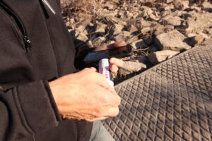  A volunteer uses nitrate test strips to test nitrate concentrations in the Des Moines River. (Photo by Cami Koons/Iowa Capital Dispatch)