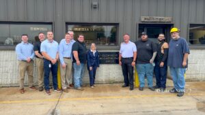 U.S. Rep. Mariannette Miller-Meeks, center, and Clow Valve Vice President and General Manager Mark Willett, standing to the right of the plaque, join Clow Valve team members outside the company’s Metal Casting Facility during Miller-Meeks’ Aug. 6, 2026, visit to Oskaloosa.