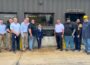 U.S. Rep. Mariannette Miller-Meeks, center, and Clow Valve Vice President and General Manager Mark Willett, standing to the right of the plaque, join Clow Valve team members outside the company’s Metal Casting Facility during Miller-Meeks’ Aug. 6, 2026, visit to Oskaloosa.