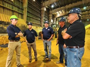  Democratic gubernatorial candidate Rob Sand, from left, with Scott Wheeler, Lincolnway Energy; Jeff Taylor, Lincolnway Energy; Chris Cleveland, Lincolnway Energy and Bill Couser, Story County farmer, tours the Lincolnway Energy ethanol plant in Nevada, Iowa, on Aug. 18, 2026. (Photo by Joanna Schroeder for Iowa Capital Dispatch)