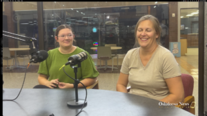 Lilia Morris and Carrie Bihn seated behind microphones during an Oskaloosa News interview about The Hub.
