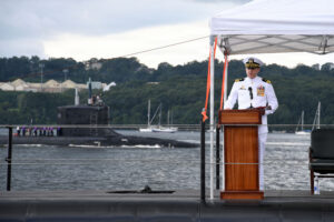 Cmdr. Kyle Haubold delivers remarks during a change-of-command ceremony for the Virginia-class nuclear-powered fast-attack submarine USS Iowa (SSN 797) aboard the Historic Ship Nautilus at the Submarine Force Museum in Groton, Connecticut, Aug. 28, 2026, as USS Hyman G. Rickover (SSN 795) passes along the Thames River. During the ceremony, Haubold relieved Cmdr. Gregory Coy as Iowa’s commanding officer. The fast-attack submarine USS Iowa and crew operate under Submarine Squadron (SUBRON) 4 whose primary mission is to provide fast-attack submarines that are ready, prepared, and committed to meet the unique challenges of undersea combat and deployed operations in unforgiving environments across the globe. (U.S. Navy photo by Chief Mass Communication Specialist Darren M. Moore)