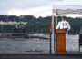 Cmdr. Kyle Haubold delivers remarks during a change-of-command ceremony for the Virginia-class nuclear-powered fast-attack submarine USS Iowa (SSN 797) aboard the Historic Ship Nautilus at the Submarine Force Museum in Groton, Connecticut, Aug. 28, 2026, as USS Hyman G. Rickover (SSN 795) passes along the Thames River. During the ceremony, Haubold relieved Cmdr. Gregory Coy as Iowa’s commanding officer. The fast-attack submarine USS Iowa and crew operate under Submarine Squadron (SUBRON) 4 whose primary mission is to provide fast-attack submarines that are ready, prepared, and committed to meet the unique challenges of undersea combat and deployed operations in unforgiving environments across the globe. (U.S. Navy photo by Chief Mass Communication Specialist Darren M. Moore)